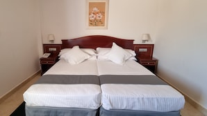 Uma cama de casal com duas almofadas, uma mesa de cabeceira com abajur e um quadro na parede.