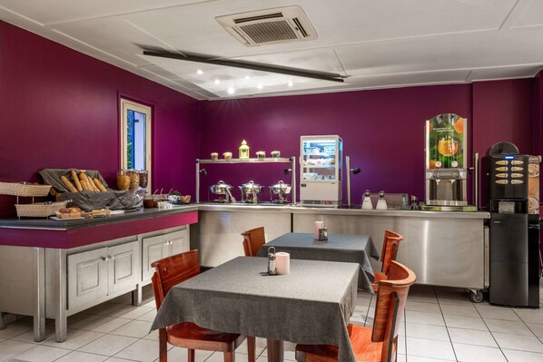 A restaurant with purple walls, a counter with bread and pastries, and tables with chairs.