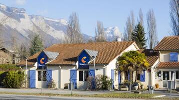 Una hilera de edificios con estructura azul y un paisaje montañoso de fondo.