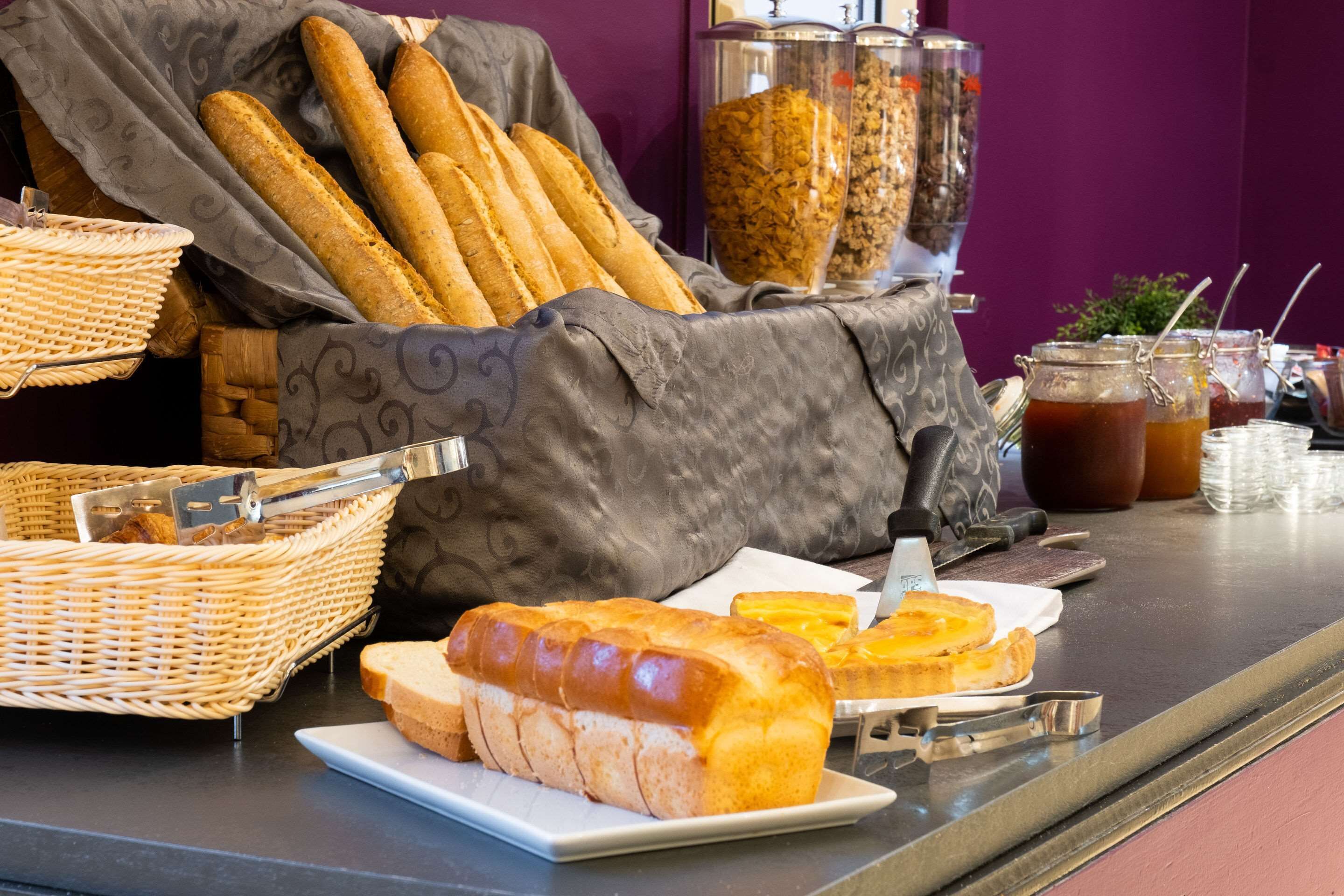 A breakfast buffet with bread, pastries, and beverages.