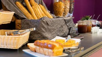 A breakfast buffet with bread, pastries, and beverages.