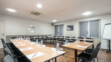 A conference room with a long table, chairs, water bottles, and a whiteboard.