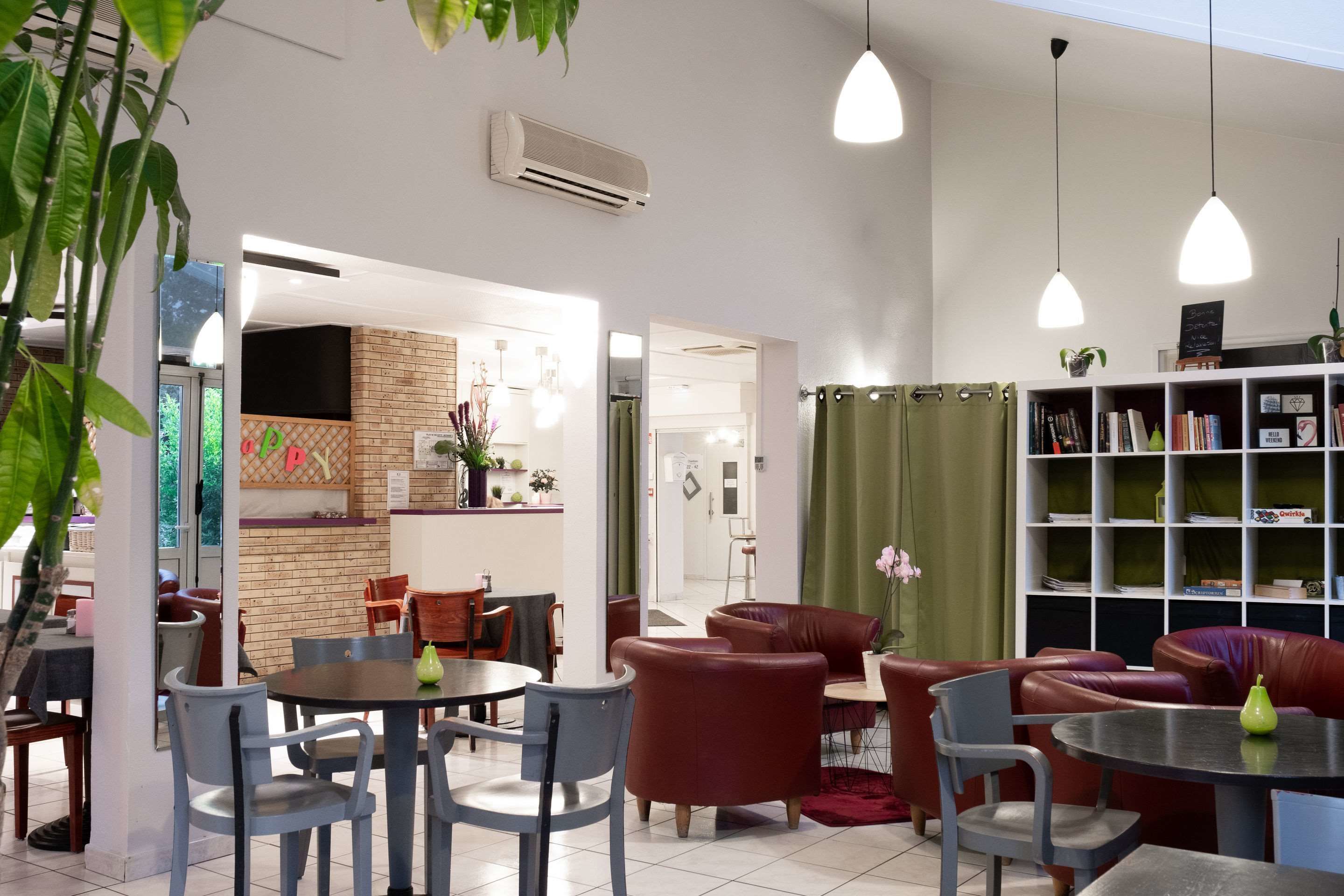 A modern interior with seating areas, a kitchen in the background, and a bookshelf.