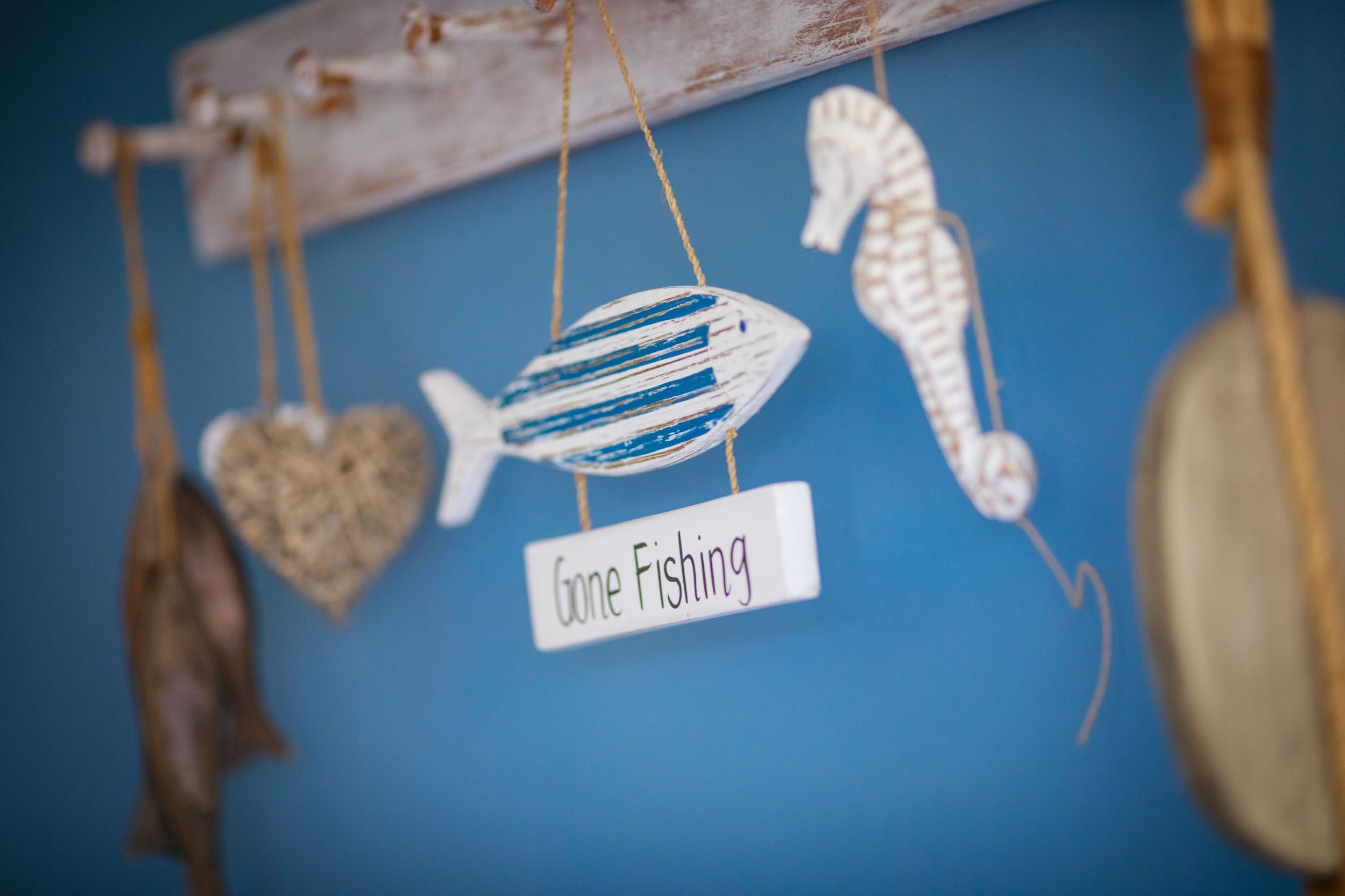 A wall with various fishing-themed decorations including a fish, a seahorse, and a heart-shaped ornament.