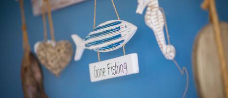 A wall with various fishing-themed decorations including a fish, a seahorse, and a heart-shaped ornament.