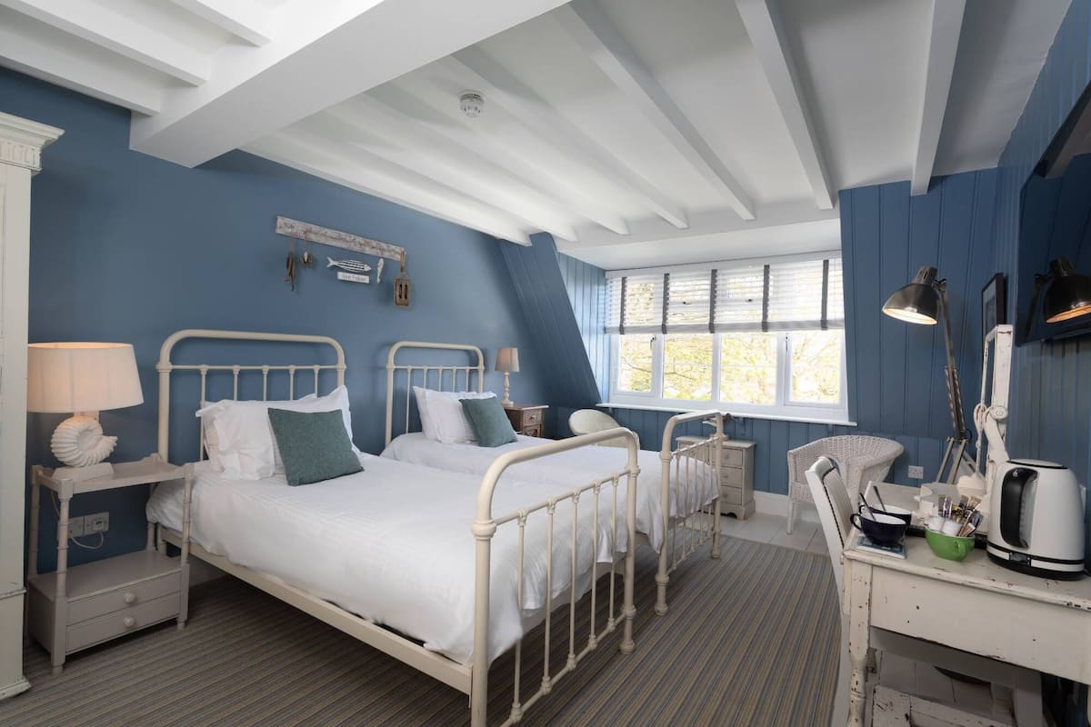 A bedroom with two beds, a desk, and a chair.
