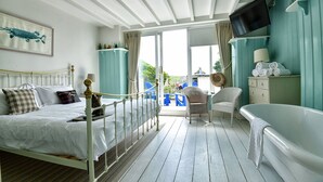 Una habitación con cama, bañera, televisor y vistas al exterior.