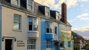 Un edificio con un letrero que dice “EATING SLEEPING DRINKING” y un mural en la pared.