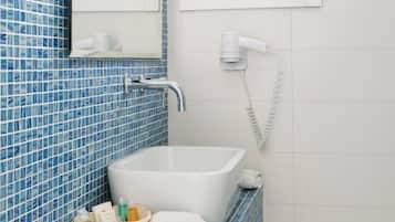 A bathroom with a white bathtub, a mirror, and a blue-tiled wall.