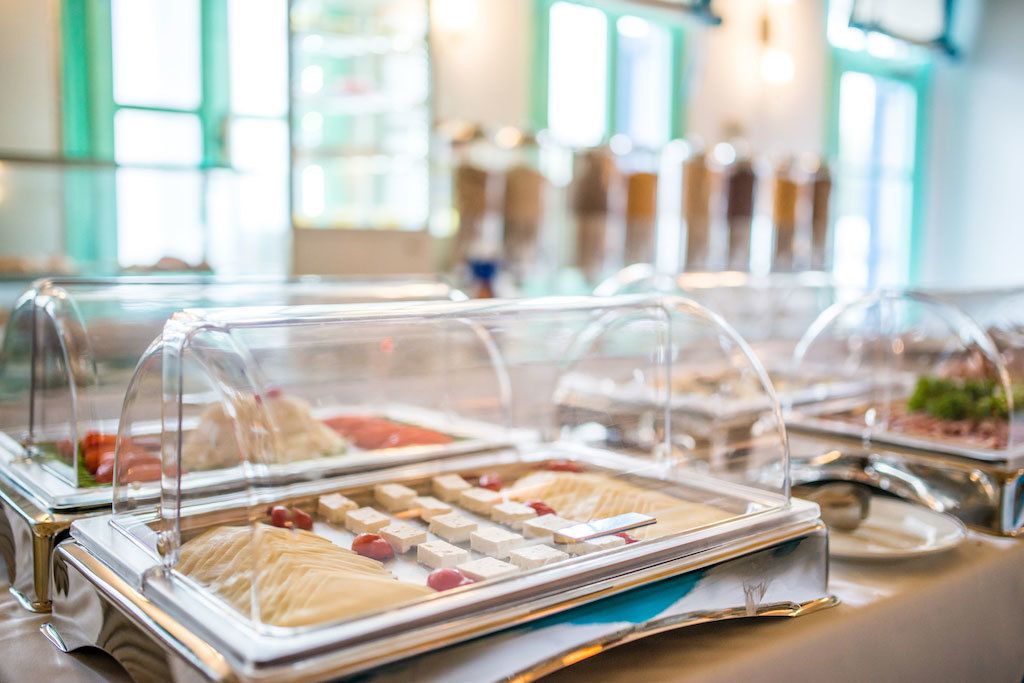 Un bufé con diferentes alimentos bajo campanas de cristal.