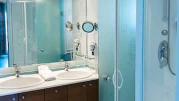 A modern bathroom with two sinks, a large mirror, and a glass-enclosed shower.