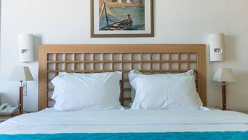 A hotel room with a wooden headboard, white bedding, two bedside lamps, and a framed painting above the bed.