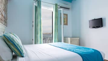 A bedroom with a bed, a TV, and a view of the sea through an open door.