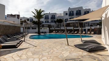 A pool area with stone flooring, lounge chairs, and a palm tree.