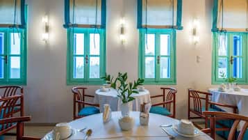 A dining area with round tables, chairs, and a central vase with greenery.