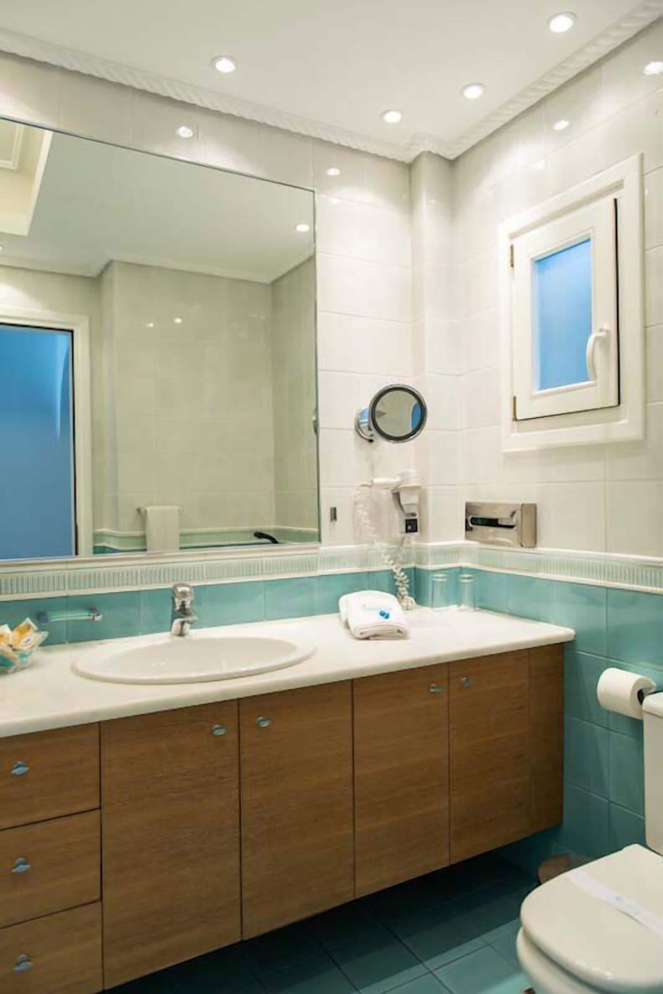 A bathroom with a large mirror, a sink, a toilet, and a towel rack.