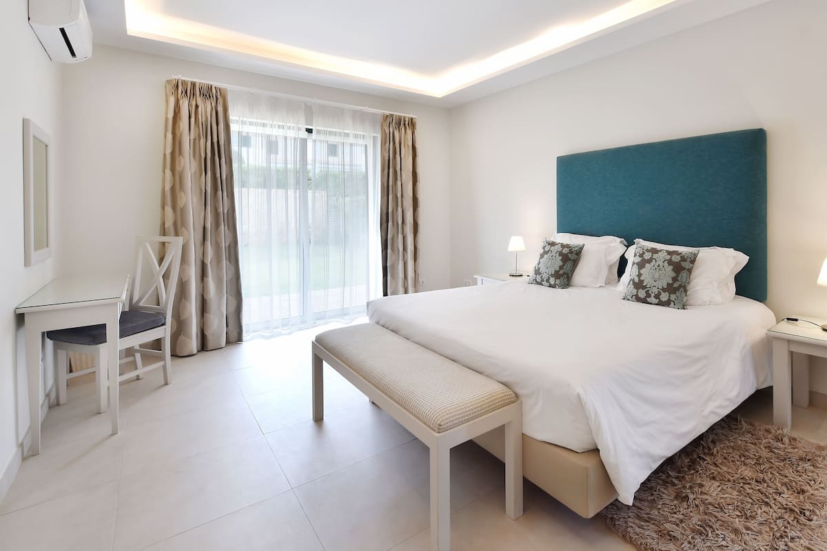 A modern hotel room with a large bed, bedside tables, a desk, and a chair.