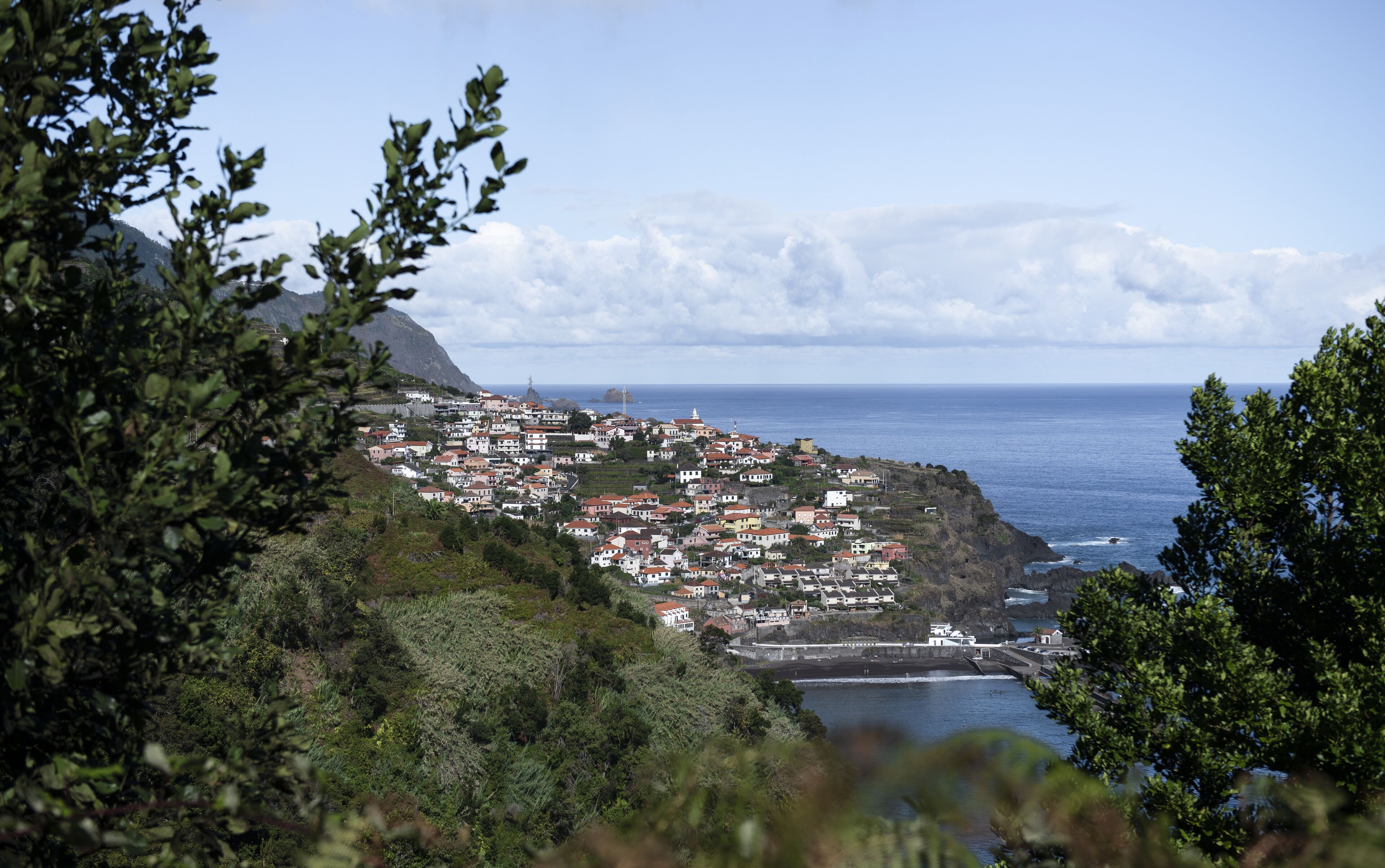 A coastal town with buildings clustered along the hillside, overlooking the sea.