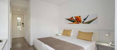 A hotel room with a large bed, a bedside table, a desk, and a ceiling fan.
