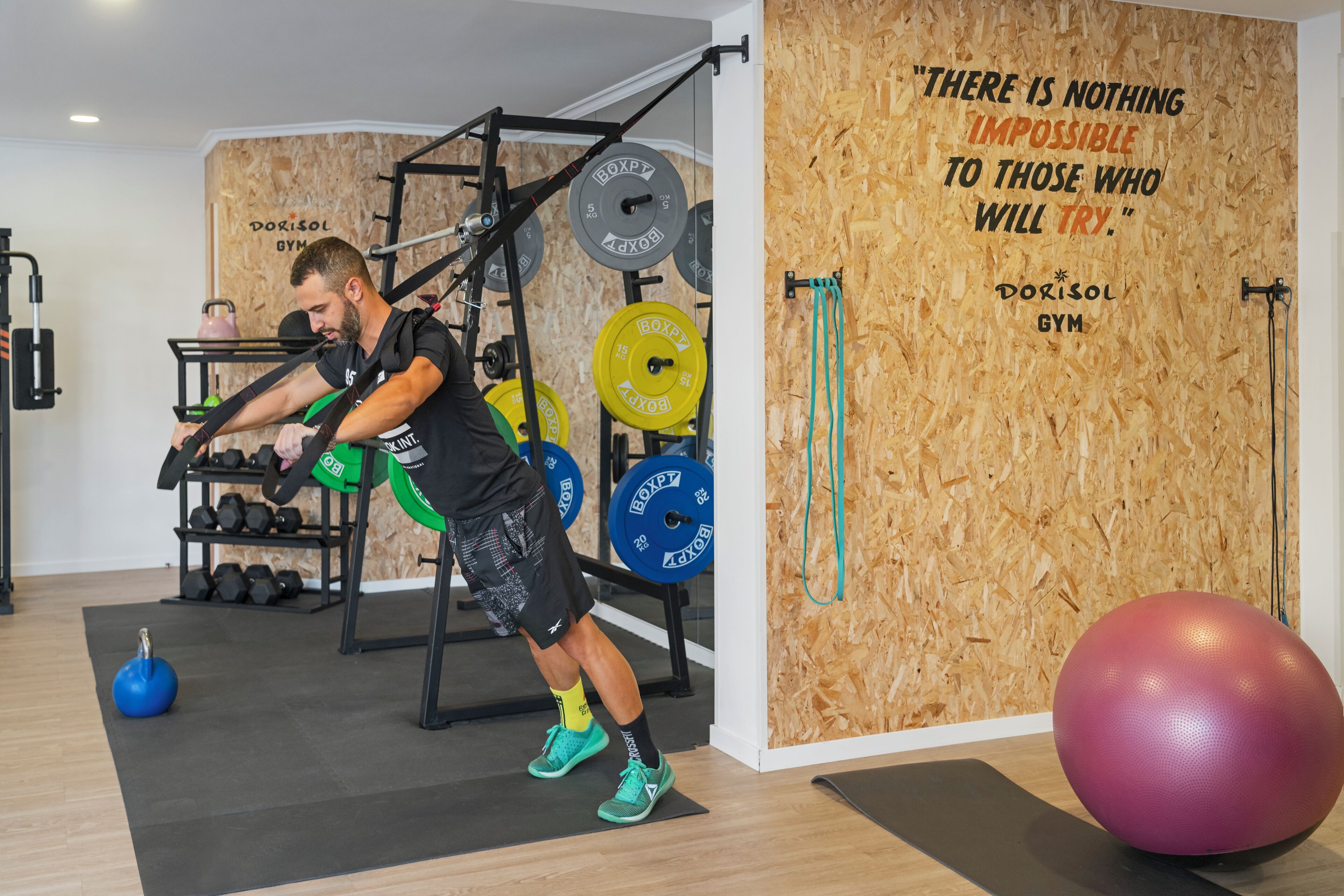 A gym with weightlifting equipment, a motivational quote on the wall, and a large exercise ball.