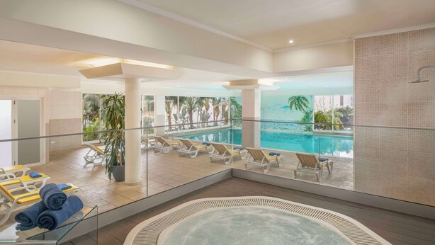 Et moderne poolområde indendørs med liggestole og jacuzzi.