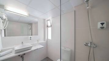 Ein modernes Badezimmer mit einer Duschkabine, einem Waschbecken mit Marmorplatte und einer Toilette.
