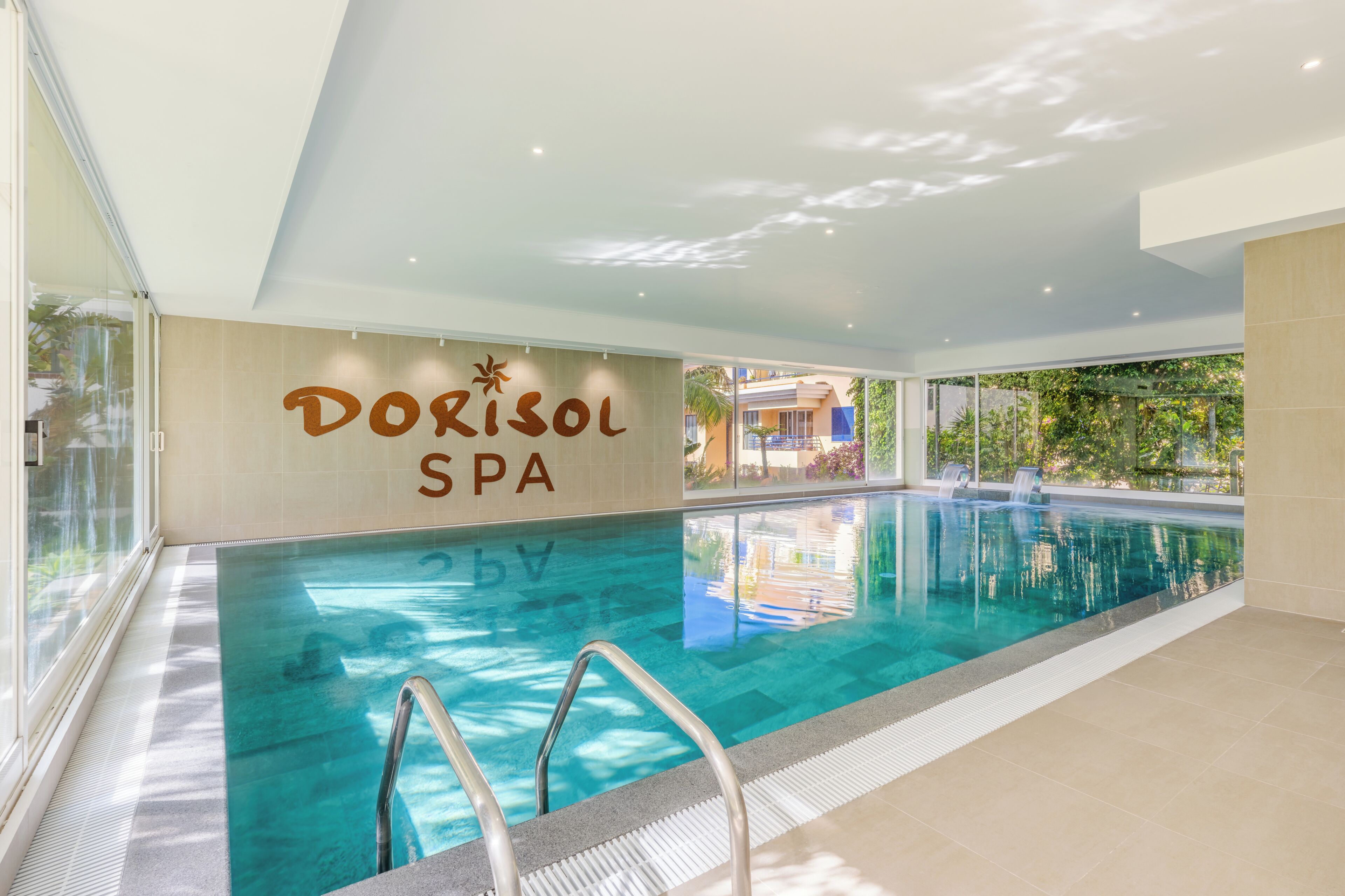 Une piscine intérieure offrant une vue dégagée sur l’espace spa, notamment sur un panneau indiquant « Dorisol Spa ».
