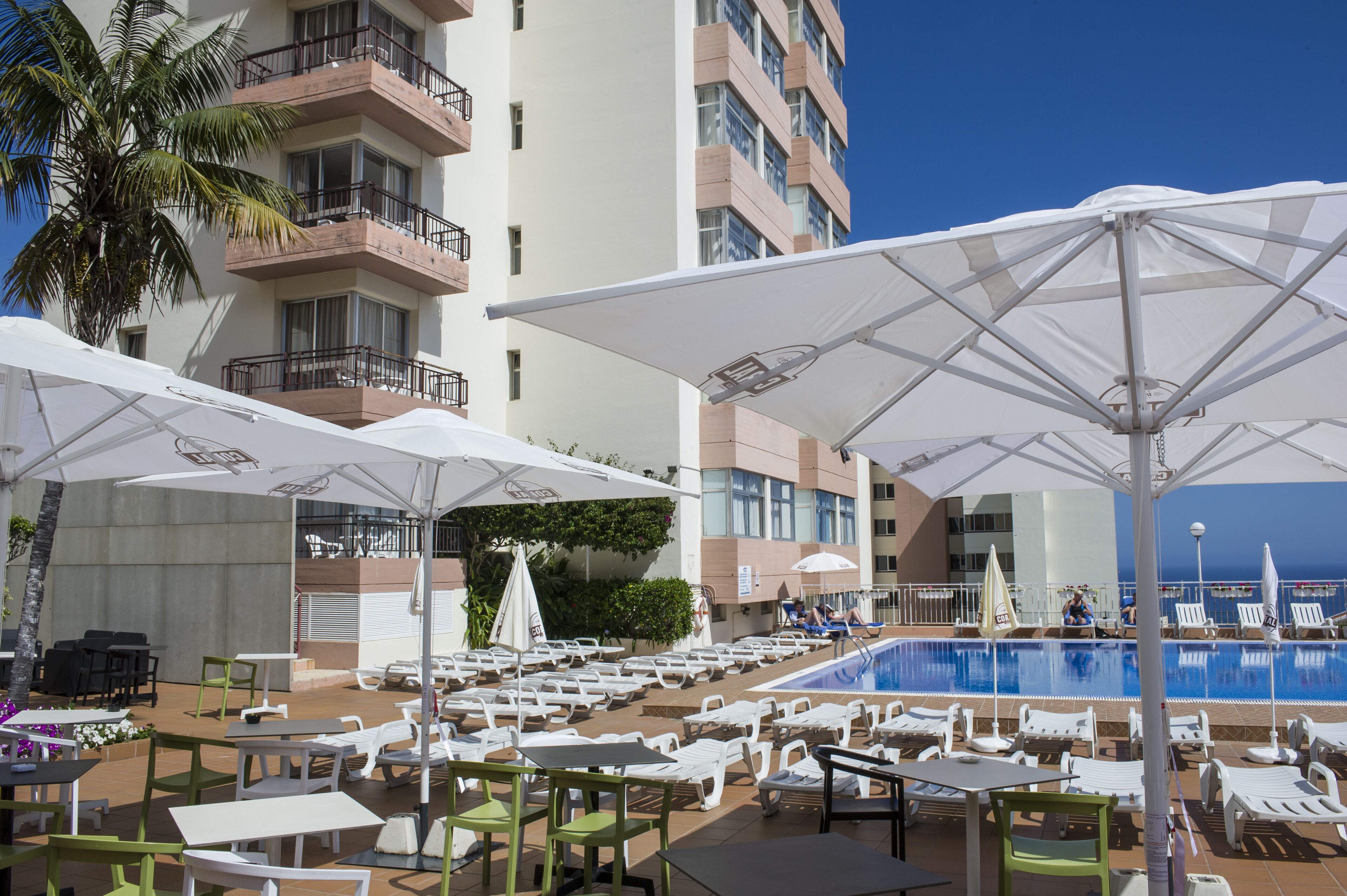 A poolside area with lounge chairs, umbrellas, and tables.