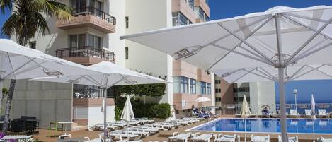 A poolside area with lounge chairs, umbrellas, and tables.