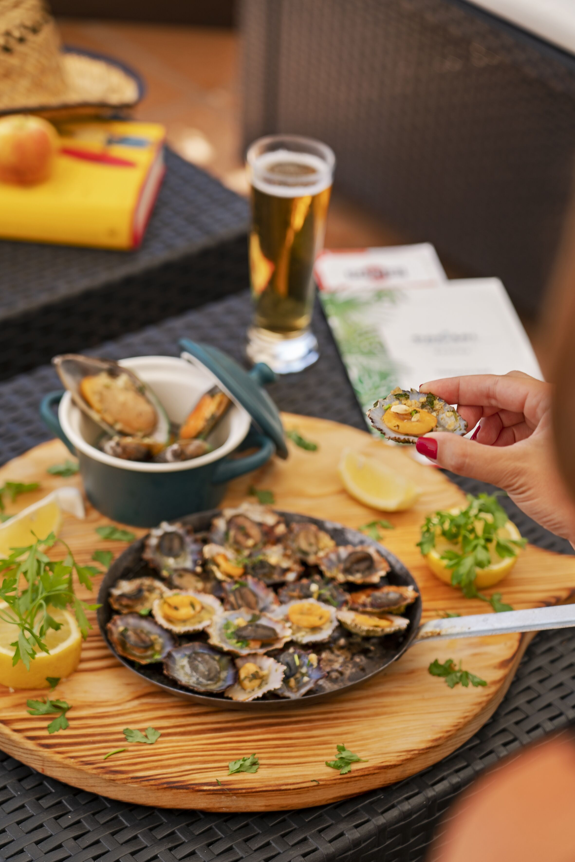 Una mesa con una fuente de ostras, un bol de ostras y una jarra de cerveza.