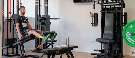 A gym with a bench press, weight racks, and a TV on the wall.