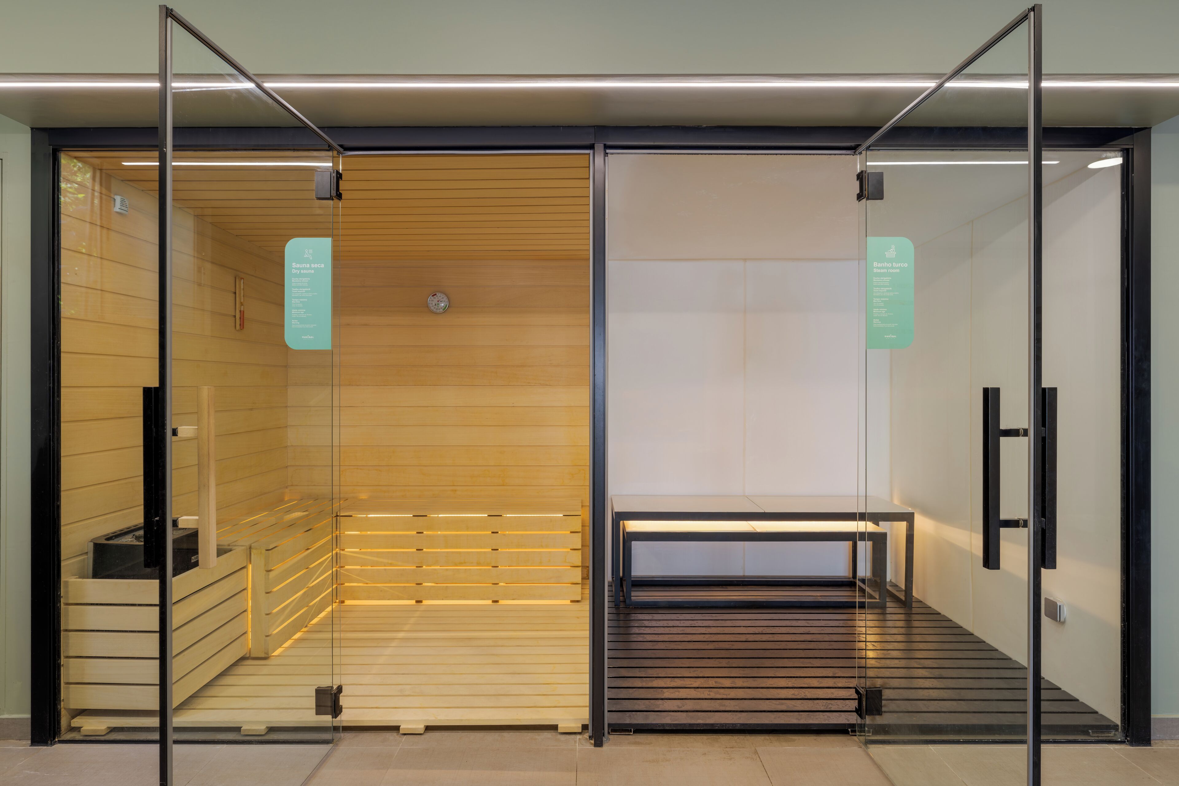 Un sauna avec un intérieur en bois, un banc et une porte en verre.