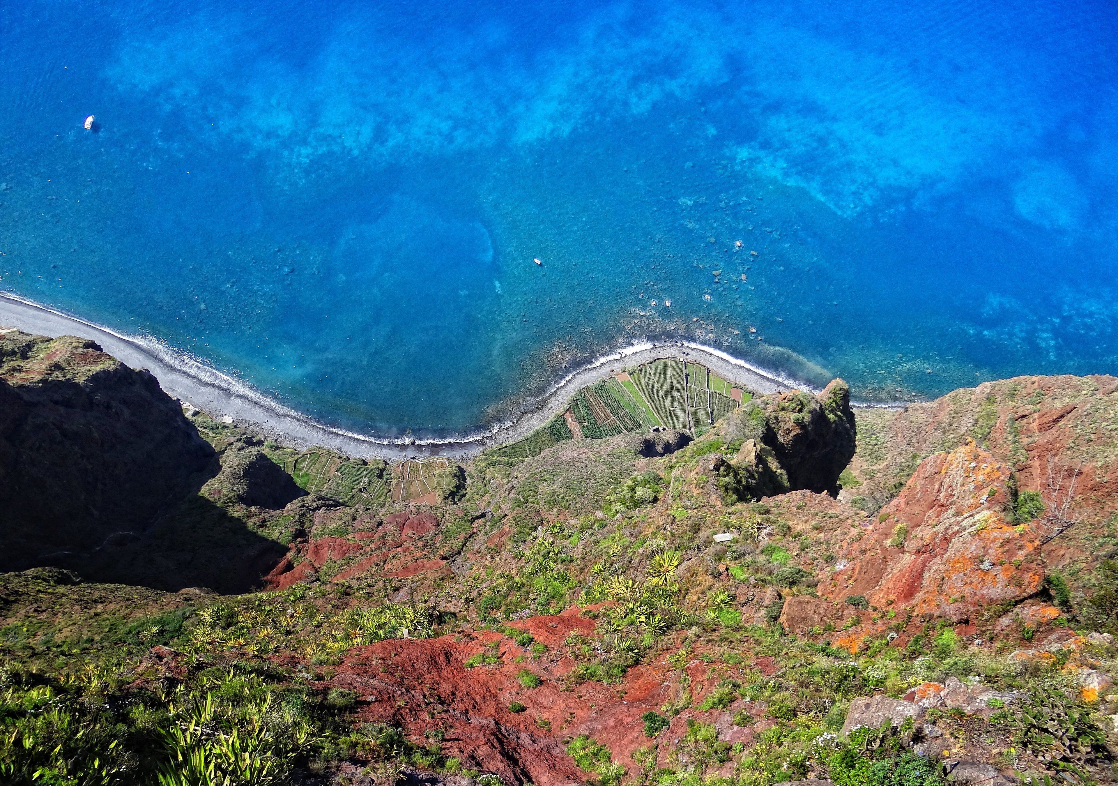 A coastal landscape with terraced fields and a winding road leading to the sea.