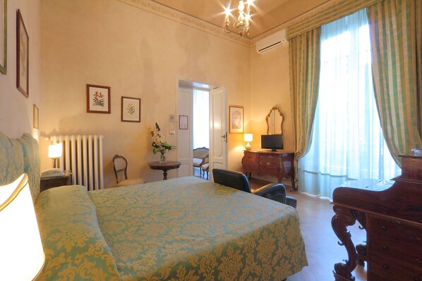 A hotel room with a large bed, a desk, a chair, a dresser, a lamp, and a television. - Hotel Villa Liana (Florence)