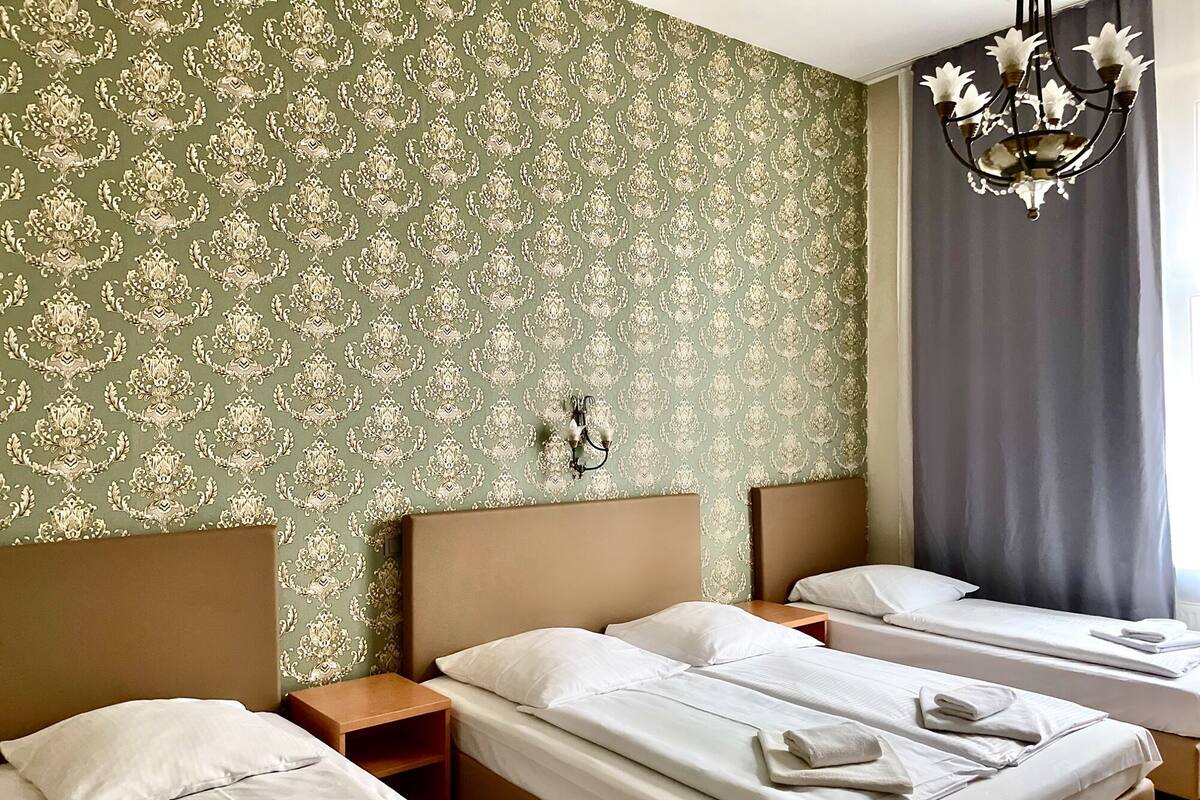 Ein Hotelzimmer mit zwei Betten, einer Kristallleuchter und einer Wand mit Muster.