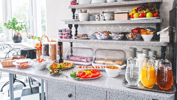 Un bufé de desayuno con diferentes alimentos, bebidas y utensilios de cocina.