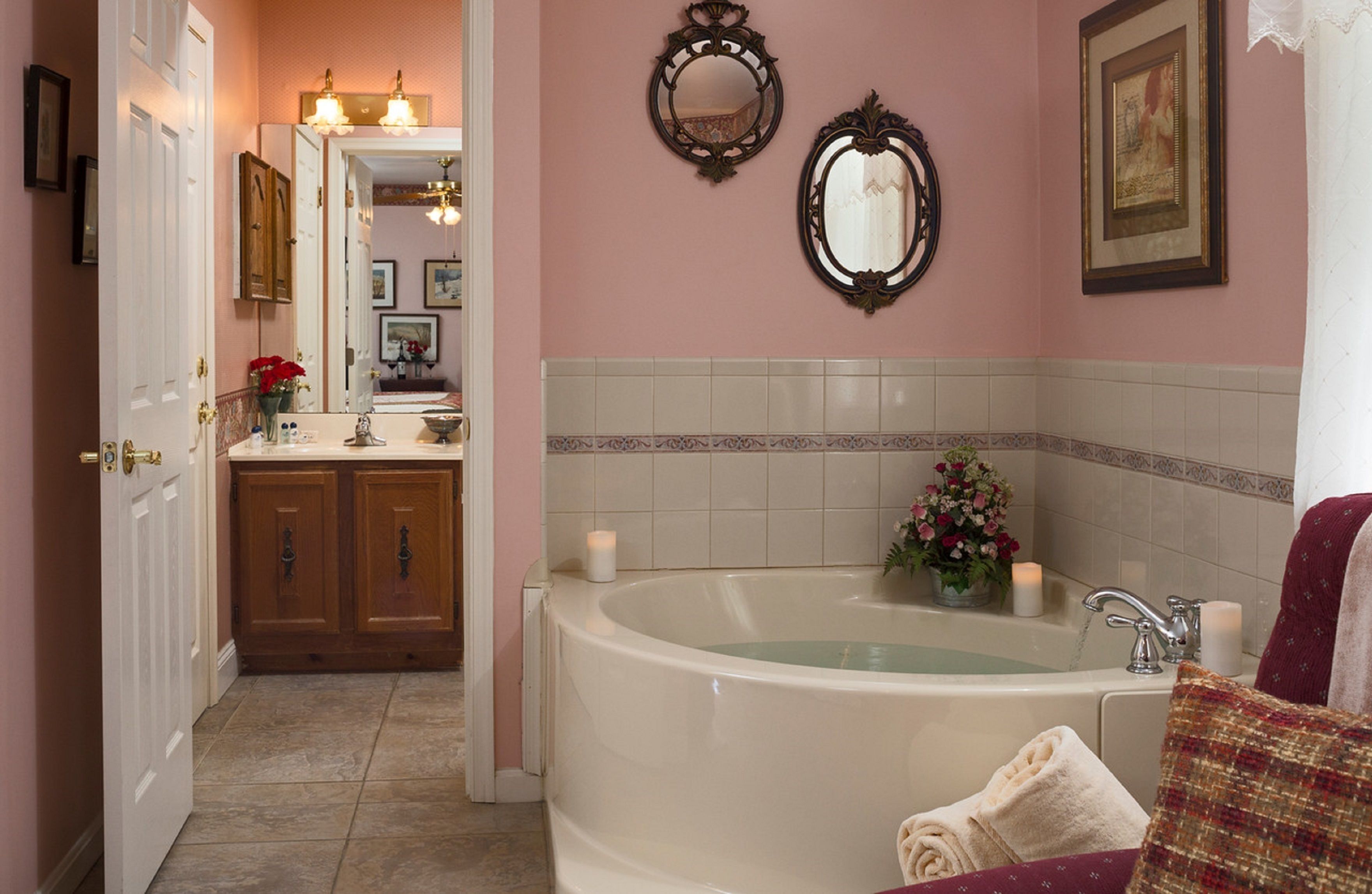 Une salle de bain avec une baignoire, un meuble-lavabo et deux miroirs.