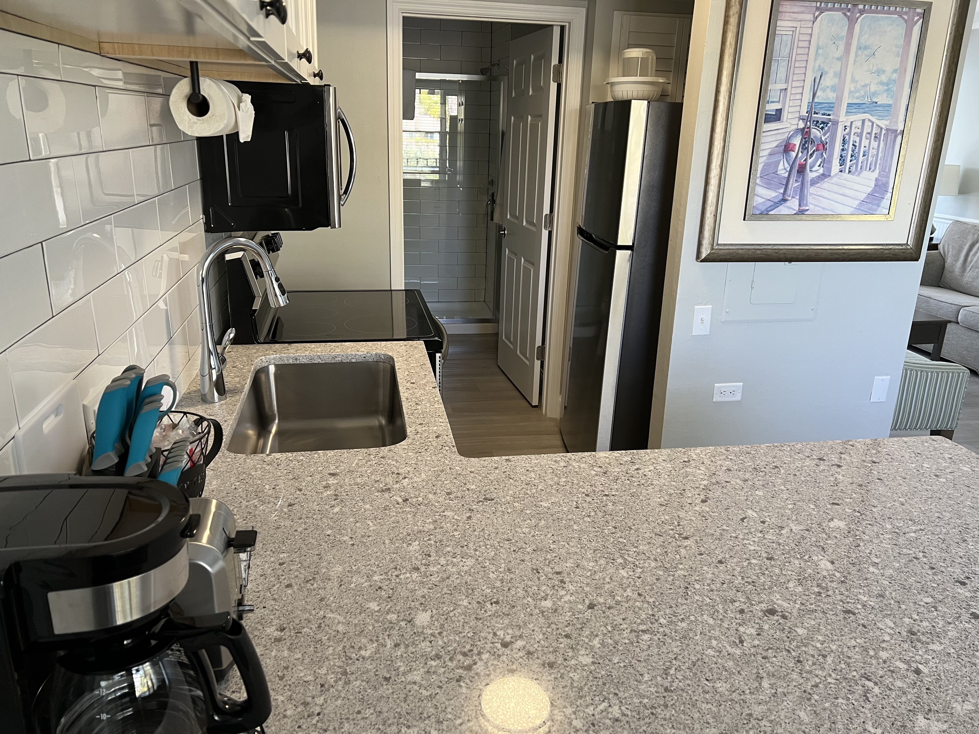 A kitchen with granite countertops, stainless steel appliances, and a view of the living area.