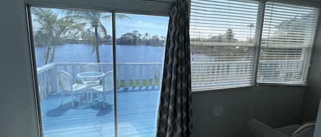 Una habitación con vistas a un lago, un balcón con mesa y sillas, y un sofá gris.