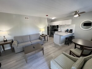 A modern kitchen with white cabinets, a central island, and a dining area with a table and chairs.