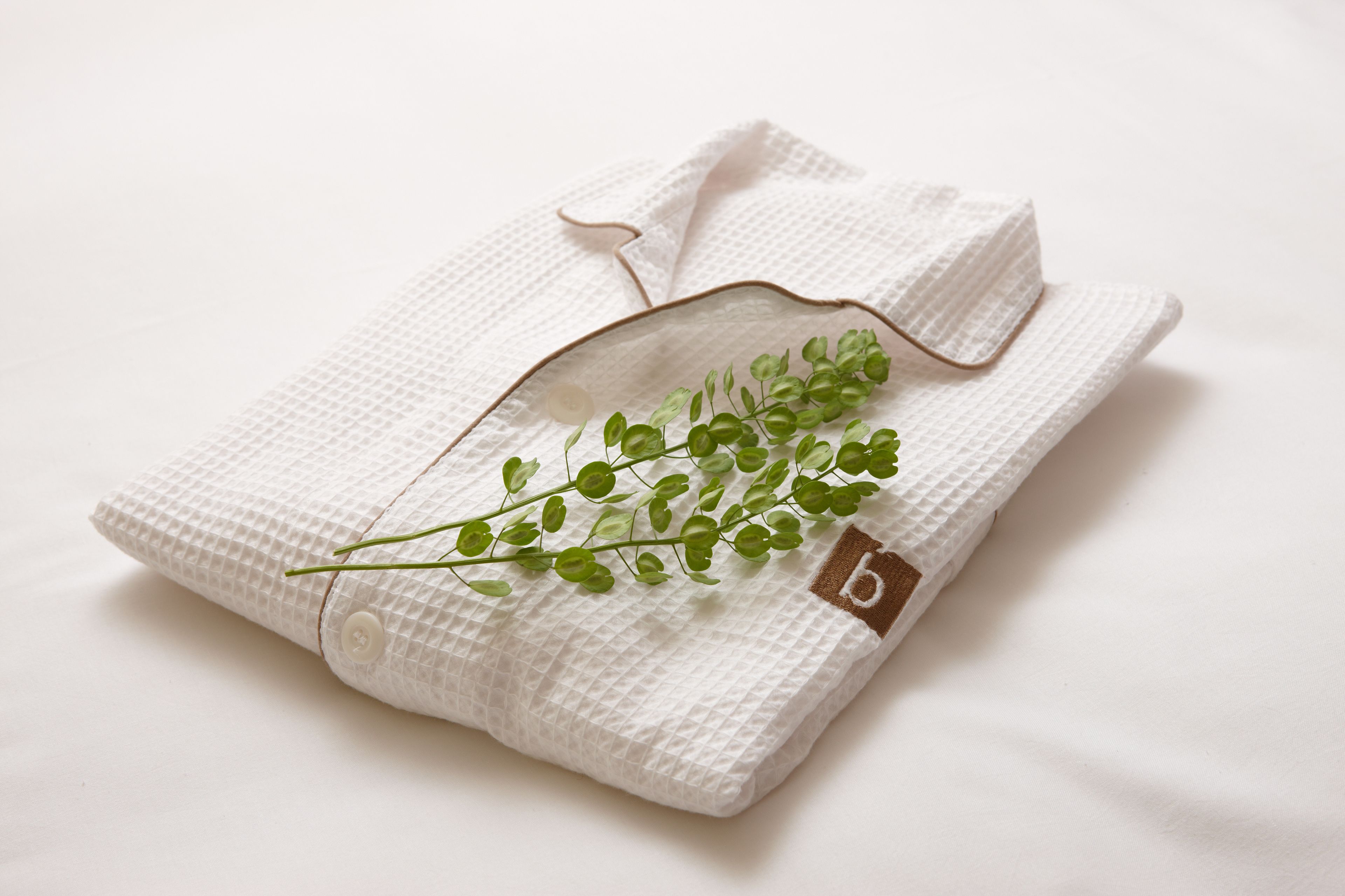 A neatly folded white garment with a small tag and a green plant.