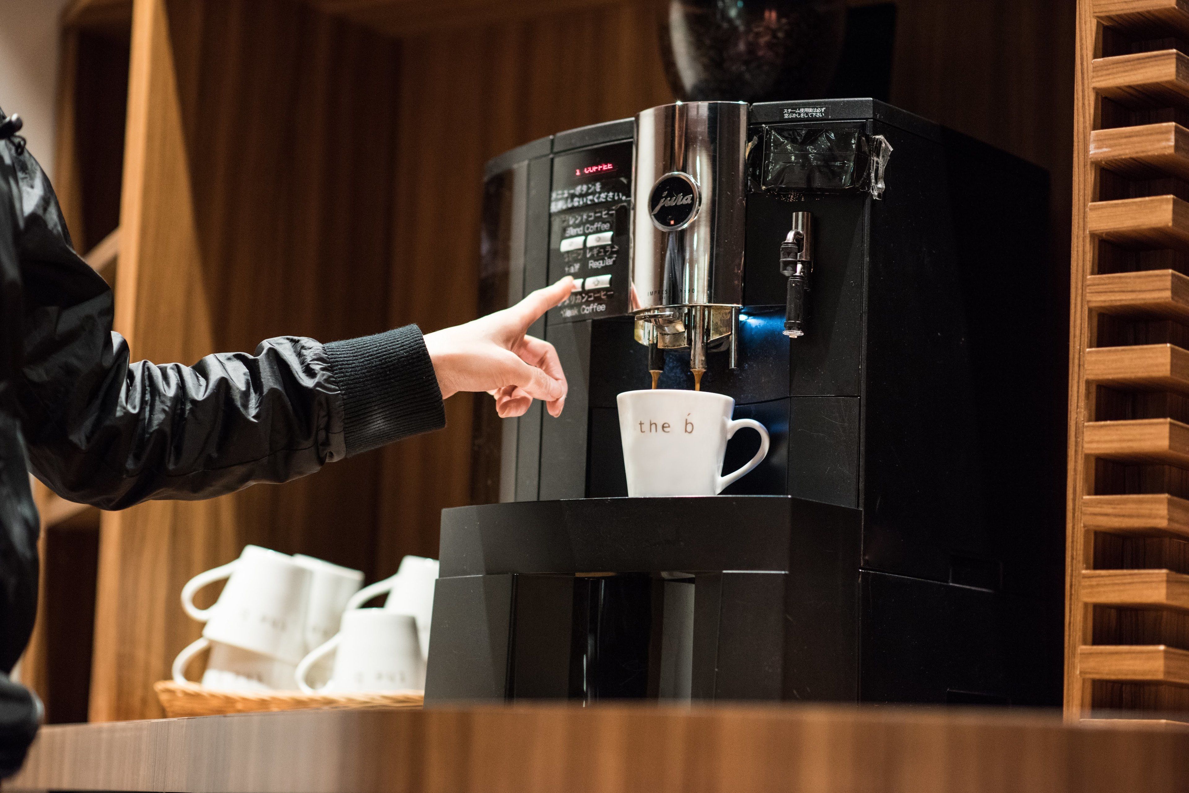 A person operating a coffee machine, with a cup placed underneath.