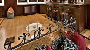 A modern bar area with wooden flooring, metal bar stools, and pendant lighting. - Cph Hotel Primavera (Tbilisi)