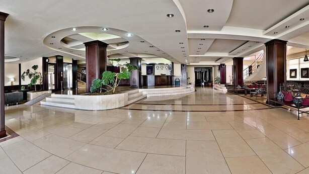 A spacious lobby with a high ceiling, multiple seating areas, and a central staircase. - Cph Hotel Primavera (Tbilisi)