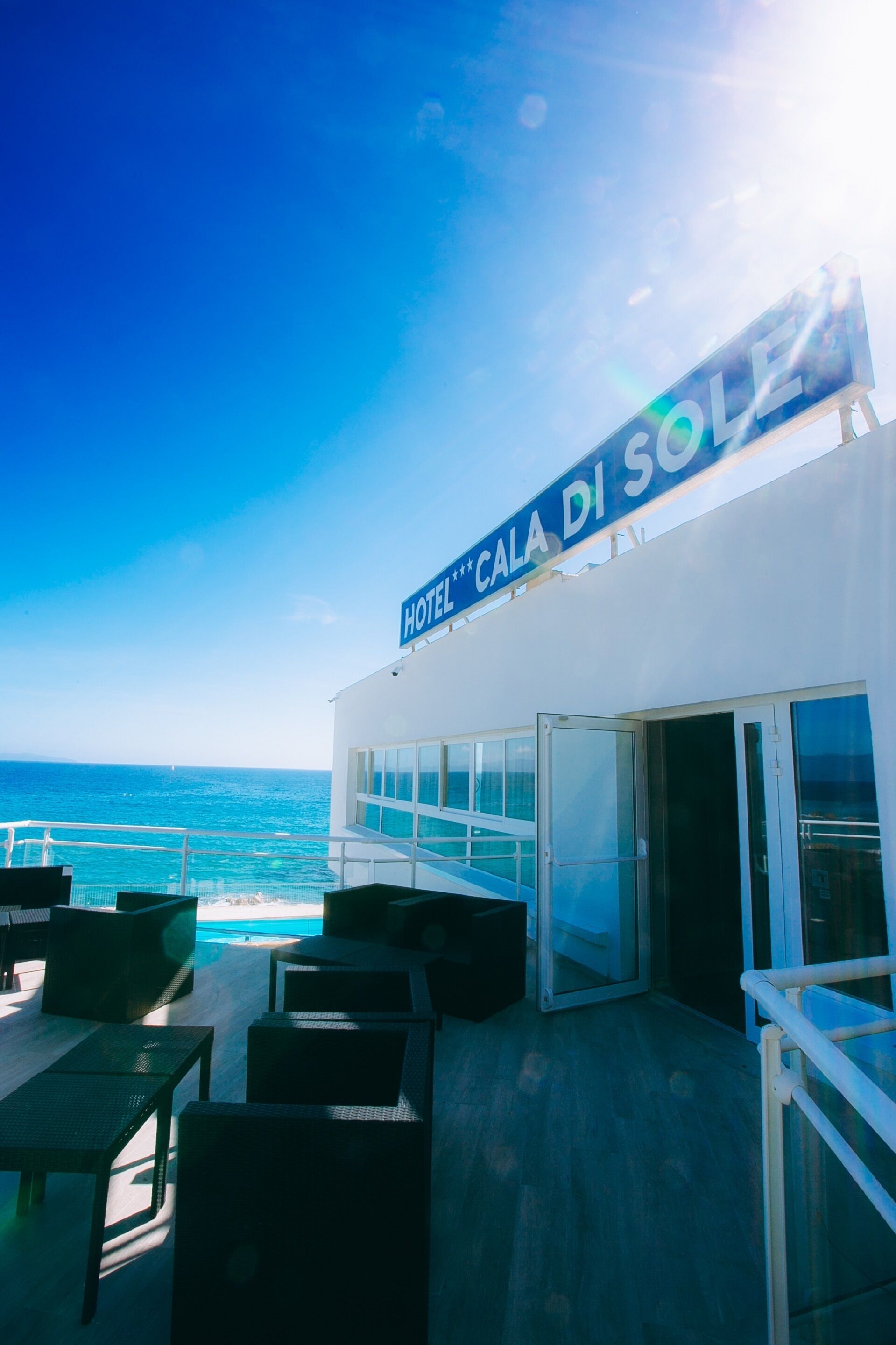 A hotel named "HOTEL CALA DI SOLE" with outdoor seating and a view of the sea.