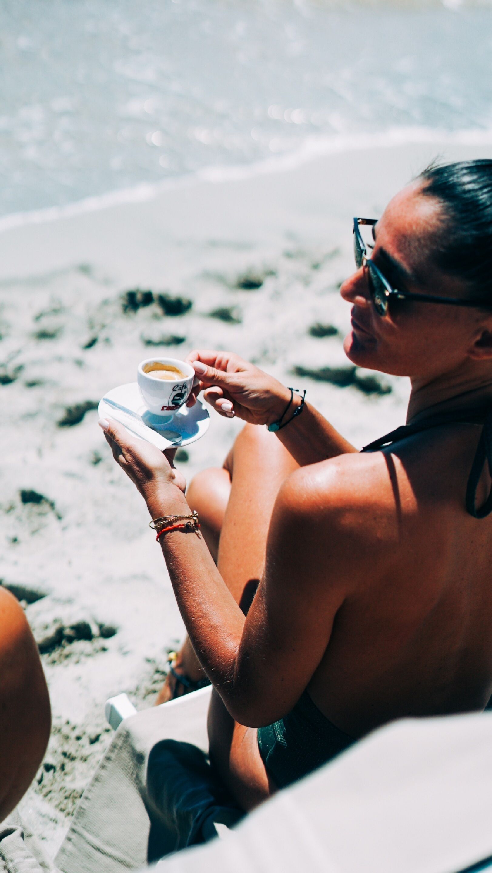 Una persona sentada en una silla de playa sosteniendo una taza de café.