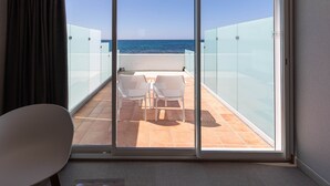 Ein Zimmer mit Meerblick, ein runder Tisch mit einem Schuhpaar und zwei Stühle auf einem Balkon.