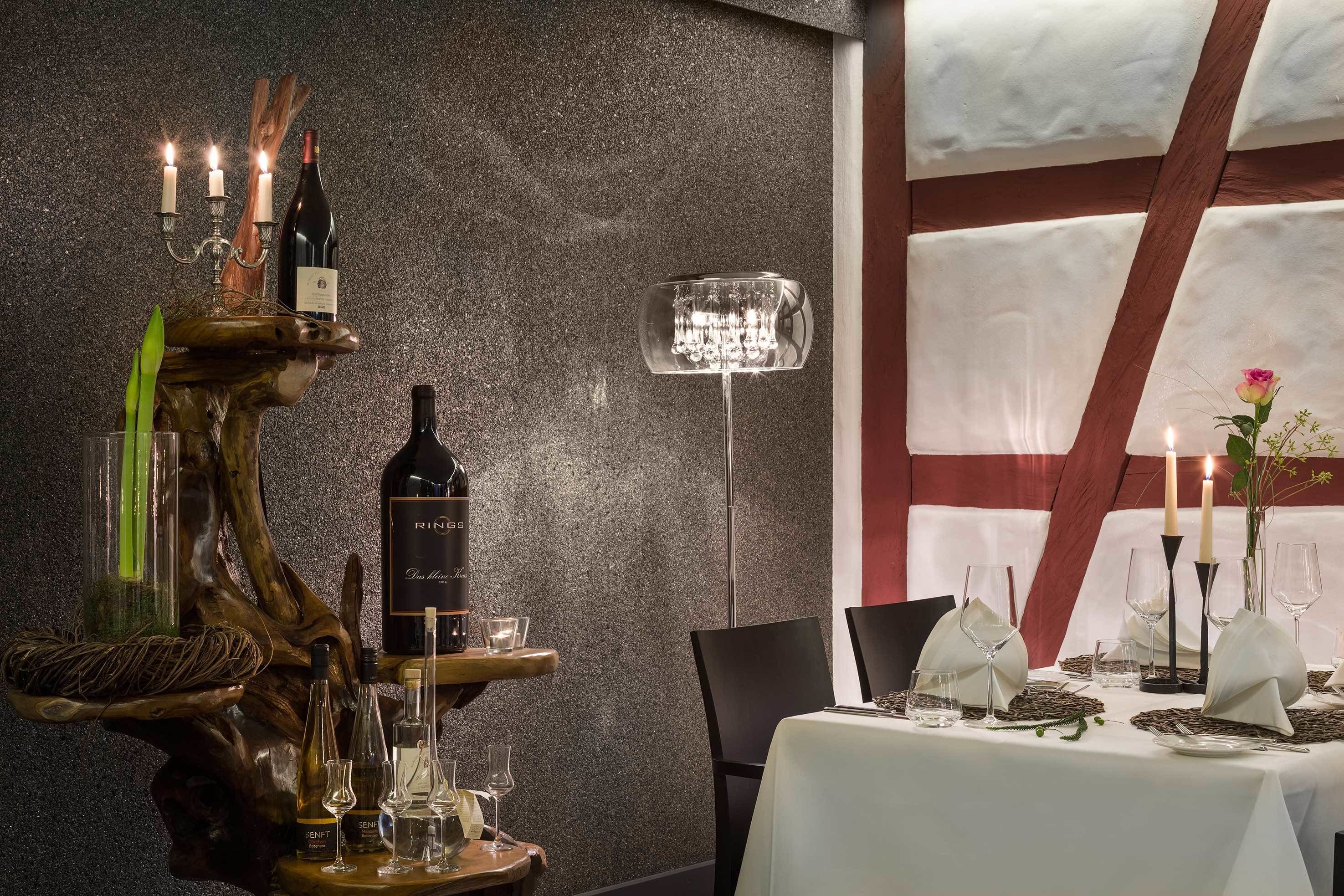 A dining table set with white tablecloths, wine bottles, glasses, and candles.