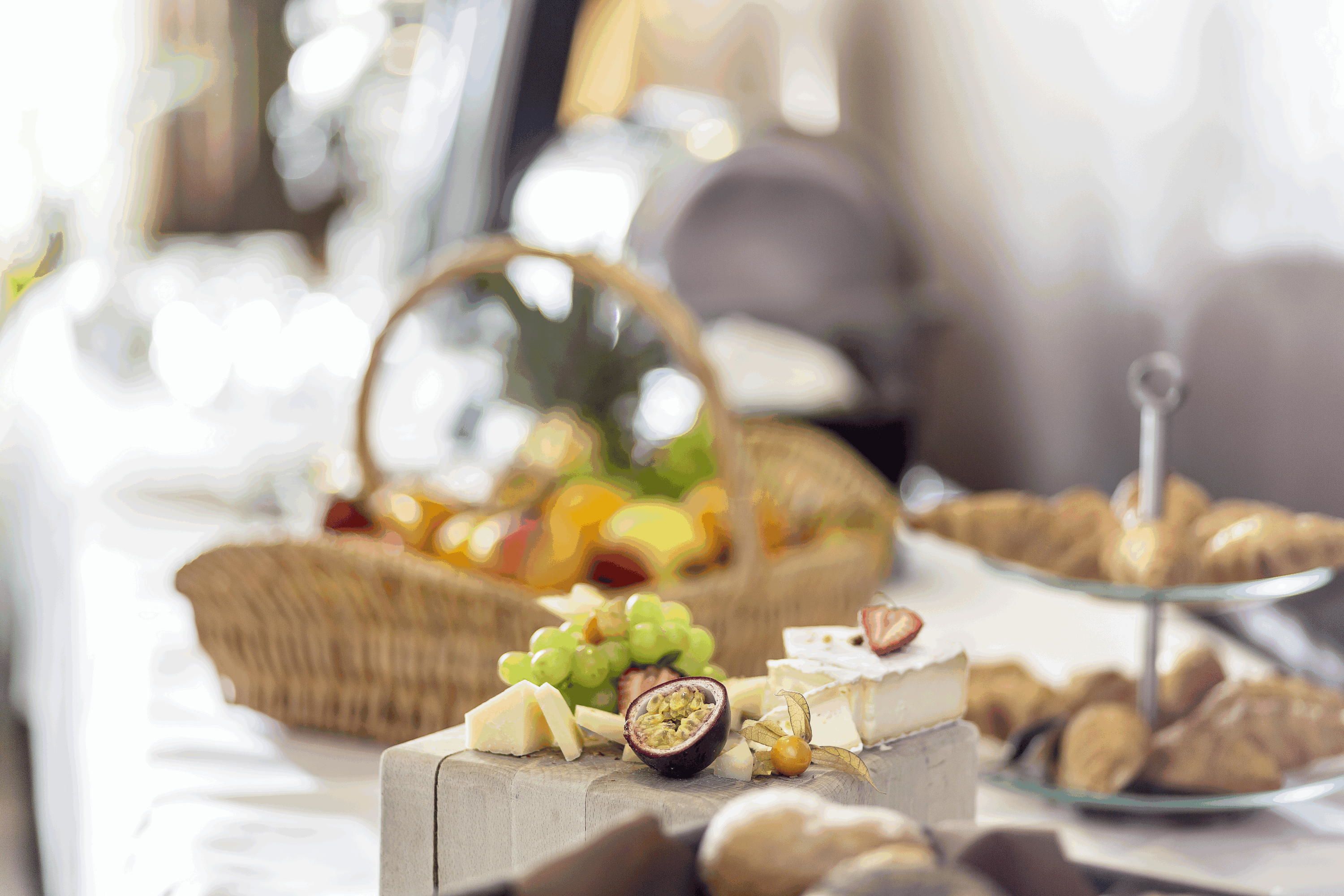 A buffet table with various cheeses, fruits, and pastries.