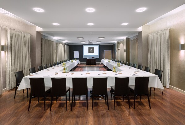 A conference room with a long table, chairs, a projector screen, and a presentation screen. - Ganter Hotel & Restaurant Mohren (Reichenau)